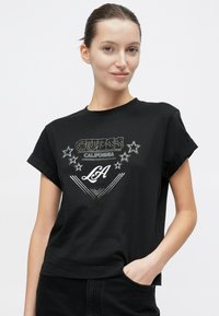 Zwart T-shirt met korte mouwen en een grafische opdruk met "Guess California" en sterren, gemaakt van gladde stof met omgeslagen manchetten.