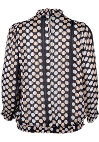 Blouse à manches longues en tissu noir transparent, présentant un motif géométrique de hexagones alternés blancs et beiges, avec un col et un ourlet volantés.