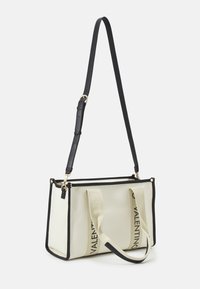 Sac fourre-tout rectangulaire beige avec bordure noire, bandoulière noire ajustable et deux poignées en tissu imprimées avec "VALENTINO" en lettres noires.