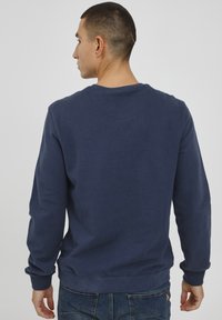 Navy blue sweatshirt with long sleeves, ribbed cuffs, and hem. Simple design with a round neckline, made from soft fabric.