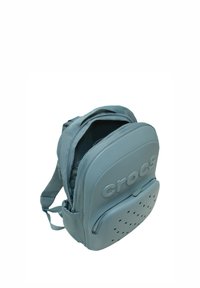 Mały niebieski plecak Crocs z dwoma zapinanymi na zamek przegrodami i regulowanymi ramiączkami, pokazany otwarty w głównej przegrodzie.