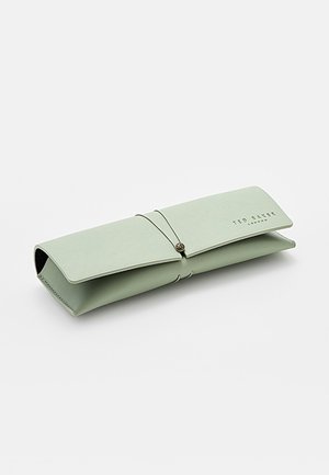Custodia per occhiali in morbida pelle verde chiaro Ted Baker con chiusura a patta e cinturino elastico, posata chiusa su sfondo bianco.