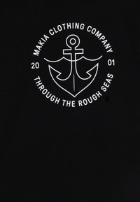 Black T-shirt featuring a central white anchor design within a circular text logo, stating "MAKIA CLOTHING COMPANY" and "THROUGH THE ROUGH SEAS."