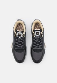 Baskets athlétiques noires et grises en mesh et daim. Dotées d'une semelle en caoutchouc texturée, d'un design à lacets et d'un intérieur à motifs.