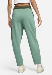 Pohodlné volné kalhoty v mátově zelené barvě s elastickým pasem, zeleným akcentem a boční kapsou. Měkká bavlněná textura, zužující se design nohavic.