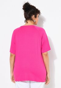 Maglietta con maniche a raglan di un vivace rosa. Tessuto liscio, vestibilità comoda e orlo curvo. Maniche lunghe e dettagli minimi nel collo.