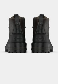 Černé kotníkové boty s hladkým koženým povrchem. Mají gumové podrážky, kontrastní prošití a ražené logo na patě.
