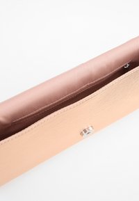 Béžová obdélníková kabelka na clutch s kovovým drukem, uvnitř prázdný hladký textil a úzká vnitřní kapsa se zipem.