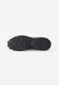 Black rubber sole with deep tread pattern and a red accent. Designed for traction, featuring prominent, angular lugs for grip.