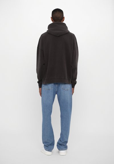 Haut de hoodie surdimensionné gris foncé avec un col montant, associé à un jean droit bleu clair et des baskets blanches. Design simple et décontracté.