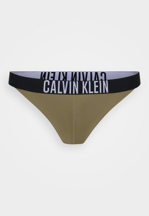 Olijfgroene thong met een zwarte elastische tailleband waarop de witte tekst "CALVIN KLEIN" staat. Glad materiaal en minimalistisch ontwerp.
