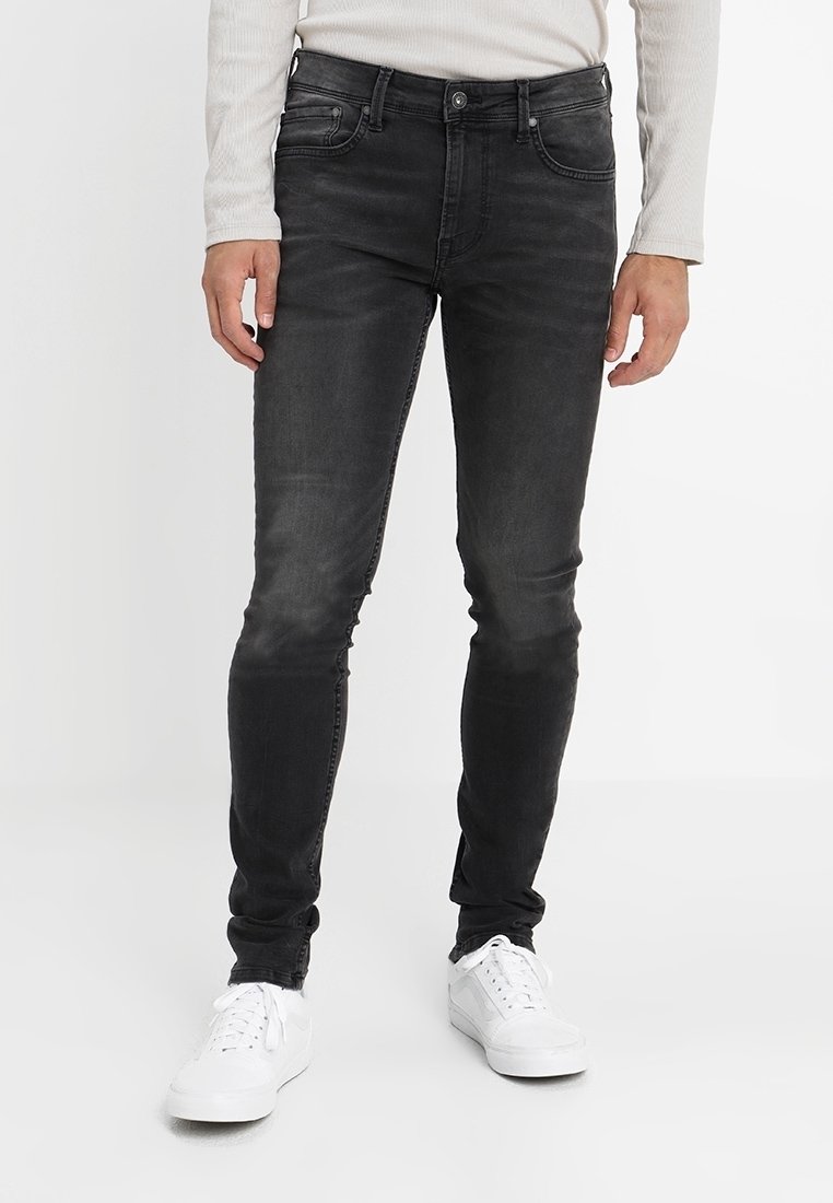 Černé slim-fit džíny vyrobené z denimu, s vybledlým vzhledem, pětikusovým designem a kombinované s bílými teniskami.