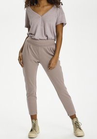 Hellblaues V-Ausschnitt-T-Shirt, kombiniert mit hellblauen, taillierten Hosen. Das T-Shirt hat kurze Ärmel; die Hosen verfügen über einen elastischen Bund und Knöchelabschlüsse.