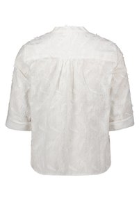 Blusa bianca a maniche corte con motivi a piuma testurizzati, dalla forma rilassata e con dettaglio della yoke posteriore con bottoni. Tessuto morbido e leggero.
