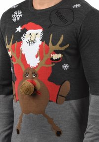 Pull en tricot gris avec un design coloré de Santa et de rennes, avec un nez en pompon, des accents de flocons de neige et des motifs texturés.