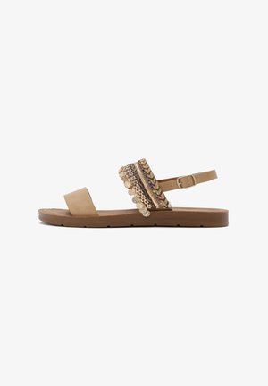 Tan leather sandal with a flat sole, featuring a decorative strap embellished with multicolored woven patterns and metal accents.