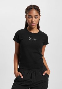 T-shirt nera con un design aderente e maniche corte, caratterizzata da un logo firmato bianco sul petto, realizzata in un tessuto morbido e traspirante.