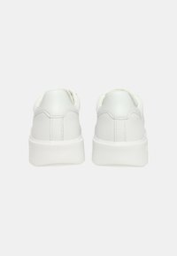 Sneakers bianchi realizzati in materiale sintetico liscio, con un design a profilo basso, punta arrotondata e suola spessa in gomma. Cuciture minimaliste sul retro.
