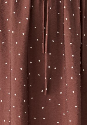 Pruun kangas valgete täppidega, millel on tekstureeritud pind ja esikinnitusdetail. Materjal näeb välja pehme ja kerge.