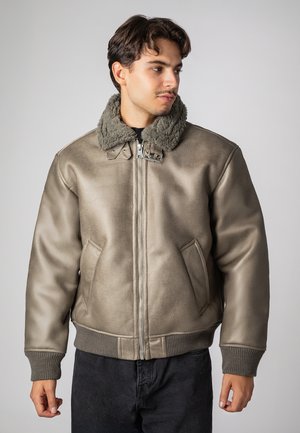 Braune Lederbomberjacke mit einem grauen Fellkragen, gerippten Bündchen und Reißverschluss. Verfügt über zwei Seitentaschen und eine strukturierte Oberfläche.