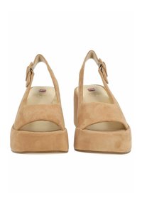 Slingback platformové boty v béžové semišové kůži, s otevřenou špičkou, zakřiveným designem a nastavitelným popruhem na přezku. Hladký povrch a minimální akcenty.