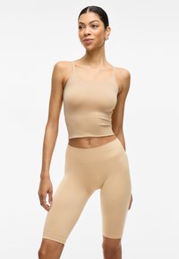 Top corto de tirantes ajustado color beige y pantalones cortos de ciclista de cintura alta, hechos de una suave tela elástica, con tirantes delgados y una cinturilla acanalada.