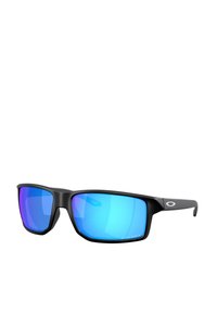 Gafas de sol deportivas negras con montura grande y angular. Lentes espejados azules con acentos morados. Logo distintivo en el brazo lateral.