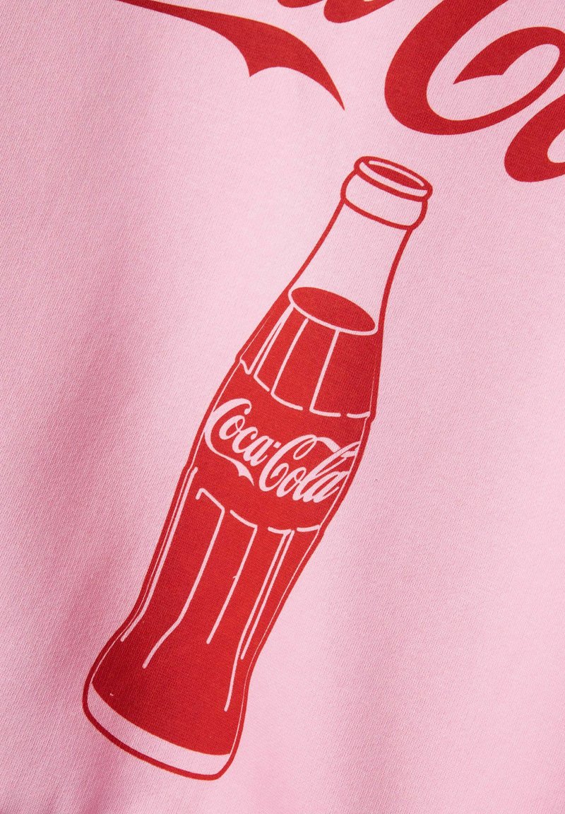 Tessuto rosa con un'illustrazione rossa di una bottiglia di Coca-Cola, che mostra chiaramente i dettagli della forma della bottiglia e del logo.