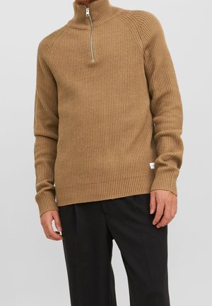 Maglione a coste di colore marrone chiaro con colletto alto e mezza zip. Presenta maniche lunghe e una vestibilità comoda. Morbida al tatto con un'etichetta laterale.
