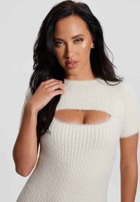 Balta mezgimo suknelė su briaunotu tekstūru, trumpomis rankovėmis ir stačiakampiu pjūviu krūtinėje. Minkšta, pūkuota medžiaga, su prigludusia siluetu.