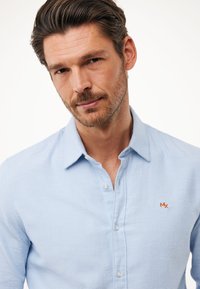 Lichtblauw button-up shirt van gestructureerde stof met een kraag en een oranje geborduurd logo op de linkerkant van de borst.