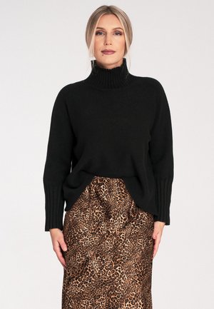 Schwarzer gestrickter Rollkragenpullover mit gerippten Bündchen, kombiniert mit einem Satinrock im Leopardenmuster mit elastischem Bund.