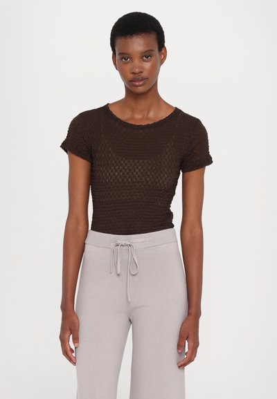 Brown textured short-sleeve top with a round neckline, paired with light gray drawstring pants, showcasing a relaxed fit and soft fabric.