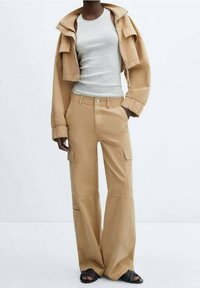 Tan cargo bukser med brede ben, to sidelommer og lukning foran. Kombineret med en lysgrå tanktop og en matchende kort jakke.