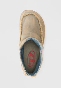 Scarpe slip-on in denim color beige con bordi sfrangiati e fodera interna blu. Presentano un logo rosso sulla soletta e una suola in gomma texture.