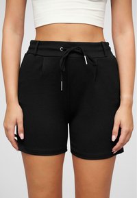 Svart bomullsshorts med elastisk midje, justerbar snøring og to sidelommer. Glatt tekstur, knelangt design.