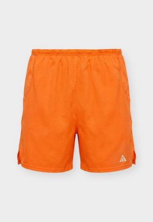 Φωτεινά πορτοκαλί αθλητικά σορτς με ελαστική μέση, πλαϊνές τσέπες, μικρό λογότυπο στο κάτω αριστερό πόδι και πλαϊνές σχισμές στο τελείωμα.