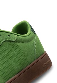 Zelene suede tenisice s teksturiranim detaljima, zakrivljenim oblikom i smešnim gumenim đonom. Imaju logo na peti i vezivanje na vezicu.