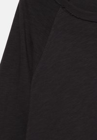 Maglia nera a maniche lunghe con texture liscia, collo rotondo e maniche raglan, con dettagli di cuciture sottili.