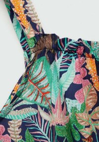 Detail látky s barevným tropickým potiskem listů a květin v zelené, růžové, oranžové a hnědé na tmavě modrém pozadí.