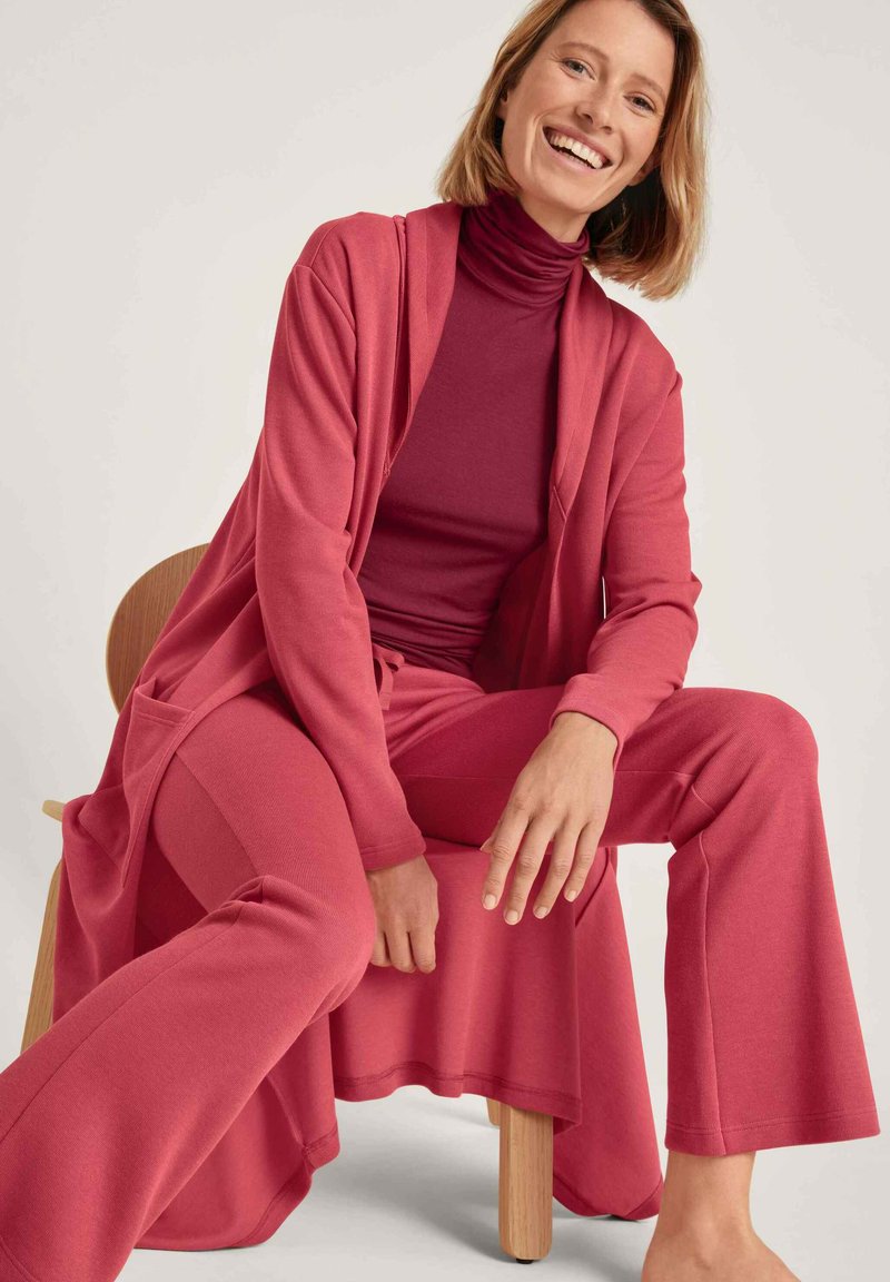 Bequemes zweiteiliges Loungewear-Set in Dunkelrot, bestehend aus einem langen Cardigan mit Taschen und einem figurbetonten Top mit hohem Kragen. Weicher, dehnbarer Stoff.