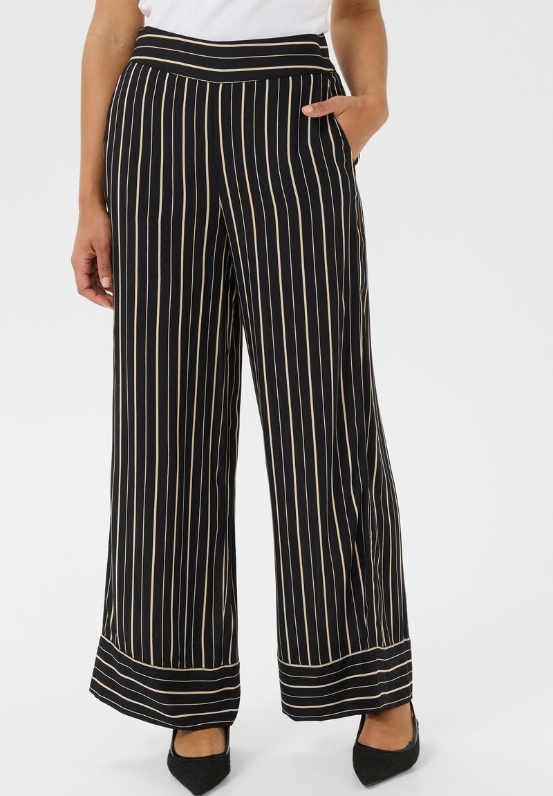 Zwart wijde broek met verticale crème strepen. Voorzien van een hoge tailleband, zijzakken en een gladde textuur, afgewerkt met een omslagzoom.