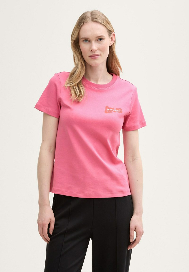 Rosa bomullströja med korta ärmar och rund halsringning, med en liten orange grafisk design på bröstet.