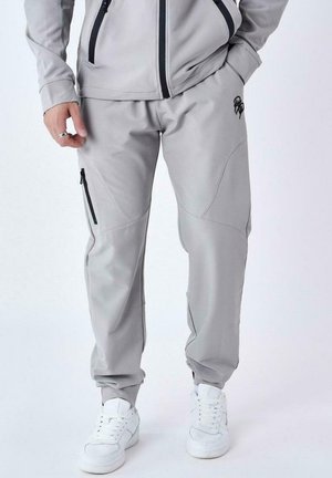 Pantalones deportivos de color gris claro, hechos de una tela suave, con bolsillos laterales con cremallera, detalles cosidos y puños elásticos en los tobillos.