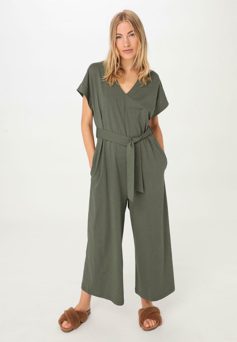 Olivgrüner Jumpsuit mit V-Ausschnitt, kurzen Ärmeln, weitem Bein und passendem Gürtel in der Taille. Aus weichem Stoff gefertigt und mit seitlichen Taschen ausgestattet.