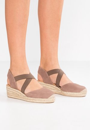 Brązowe zamszowe sandały na koturnie z plecioną juteową podeszwą, z krzyżującymi się paskami i otwartym tyłem dla wentylacji i komfortu.