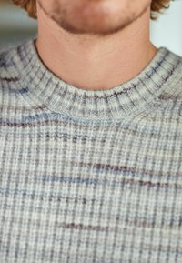 Pull en tricot avec un col rond à côtes, présentant une base gris clair et des rayures horizontales multicolores dans des tons de bleu et de marron.