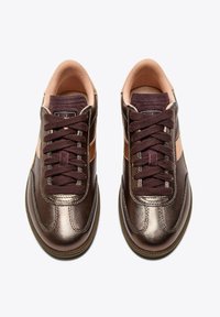 Une paire de baskets métalliques bronze avec des lacets marron foncé et une doublure intérieure rose, vue de dessus sur un fond blanc.