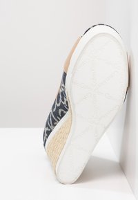 Scarpa slip-on in tela con un motivo astratto blu scuro e bianco, dettagli in pelle color beige e una suola intermedia in juta intrecciata testurizzata. Suola esterna in gomma bianca.
