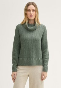 Zielony sweter z dzianiny z dużym kołnierzem, prążkowaną teksturą i plecionym wzorem akcentującym dół. Długie rękawy i luźny krój.